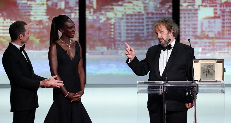 New Zealand director, screenwriter and producer Peter Jackson gestures next to US actor Elijah Wood and French-Malian actress and master of Ceremony Eye Haidara as he receives his Honorary Palme d'Or during the Opening Ceremony at the 79th edition of the Cannes Film Festival in Cannes, southern France, on May 12, 2026. (Photo by Sameer AL-DOUMY / AFP via Getty Images)